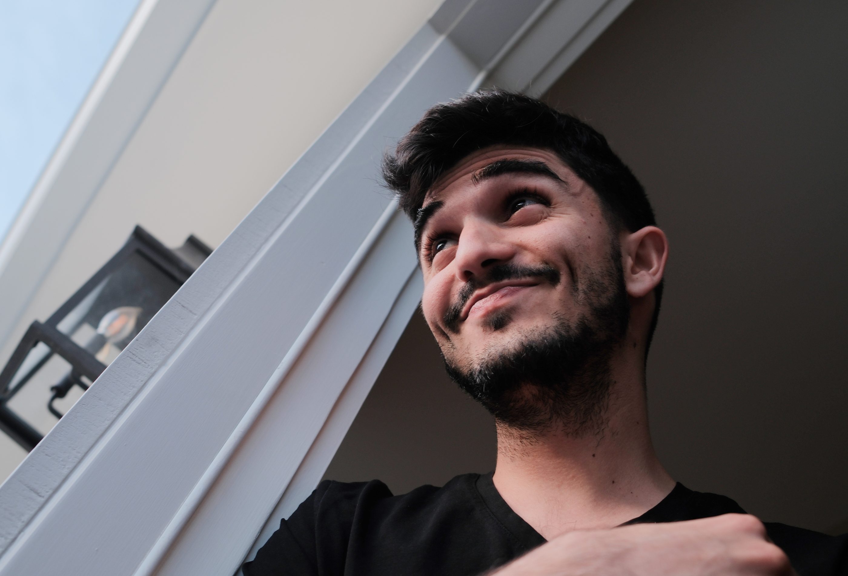 A man looking up and smiling beside a doorway.