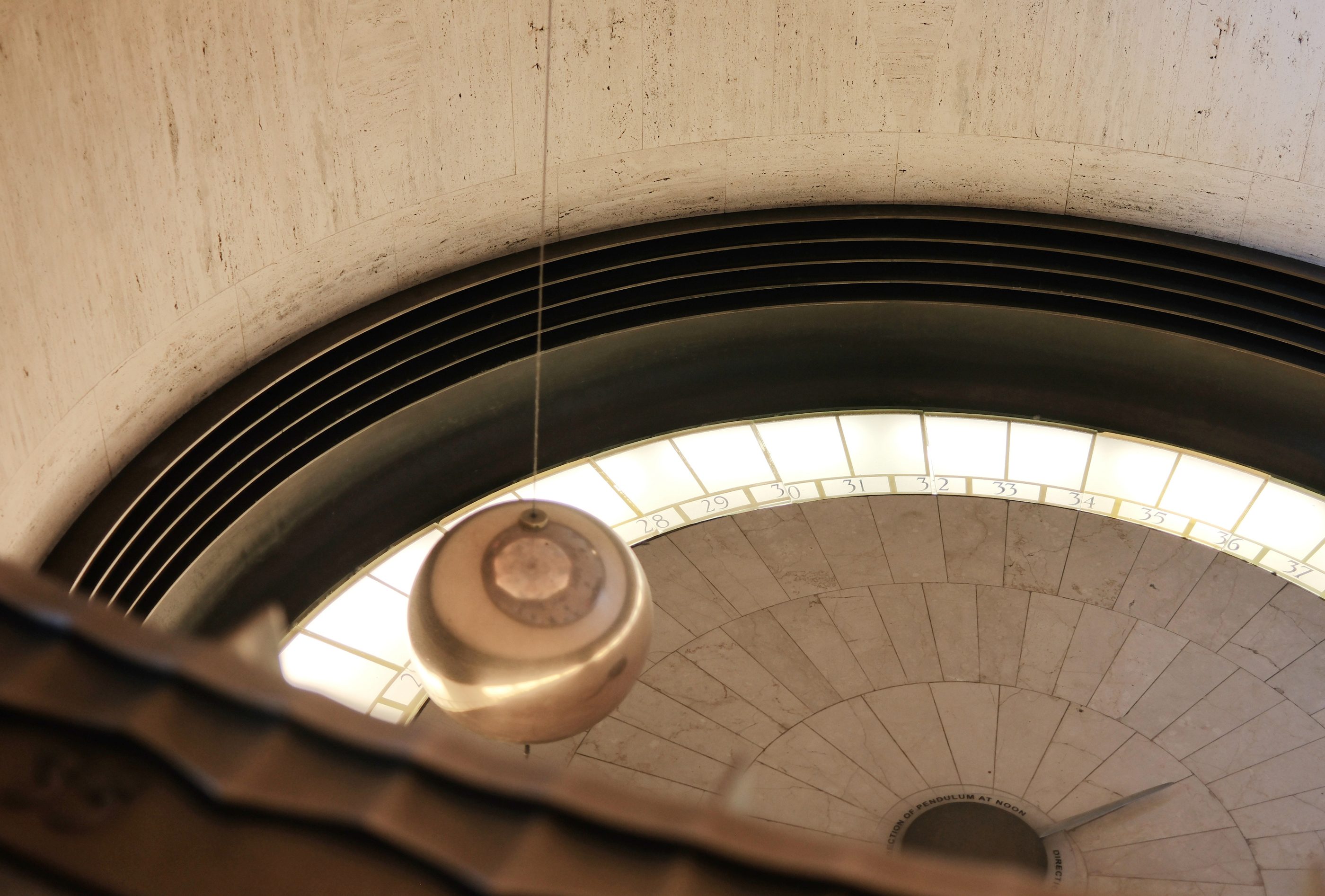 A pendulum hanging in a curved architectural alcove.